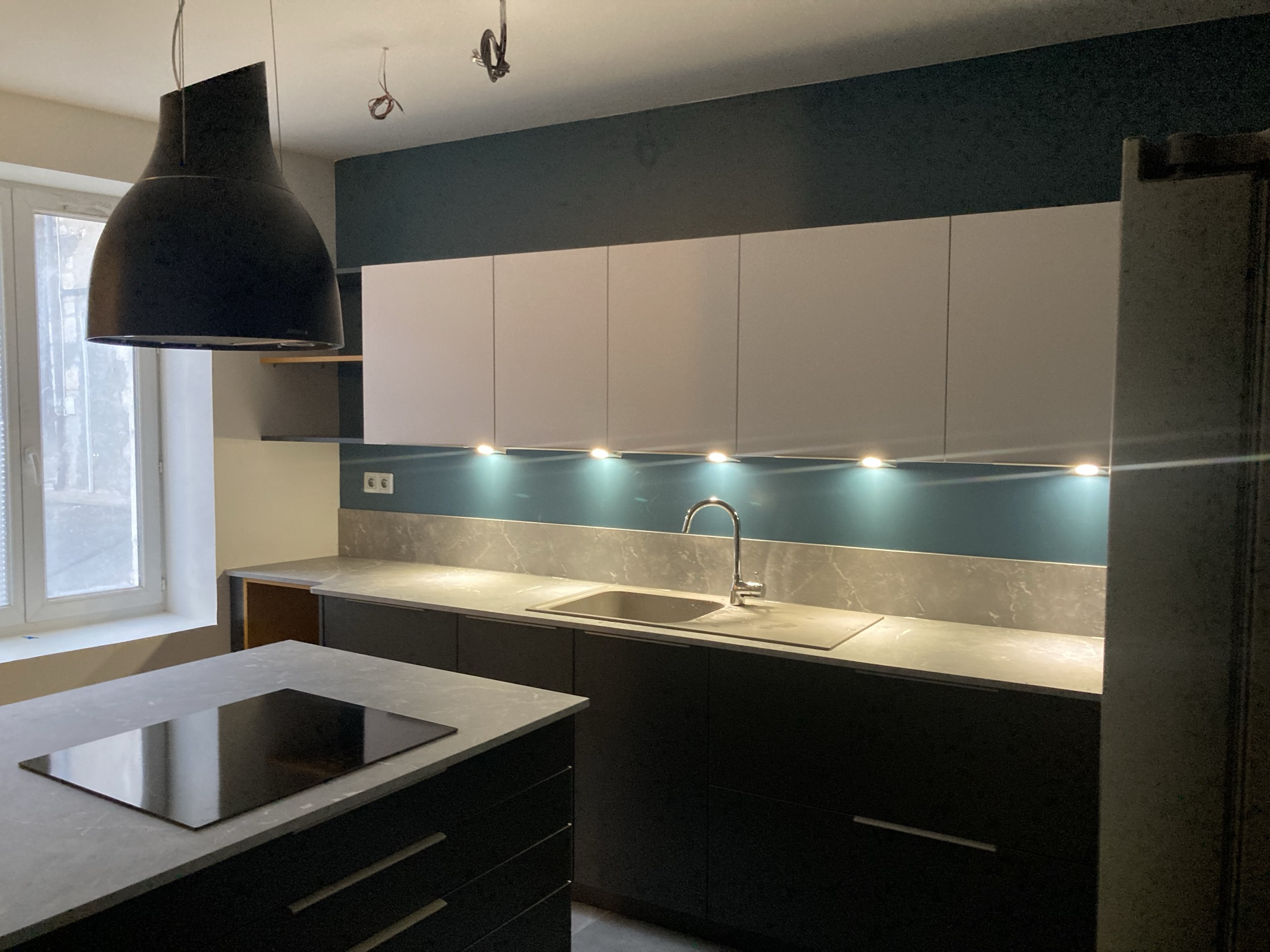 Cuisine moderne avec îlot central, crédence rétroéclairée et luminaires design